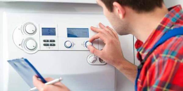 Plumber adjusting the knobs in the electric boiler.