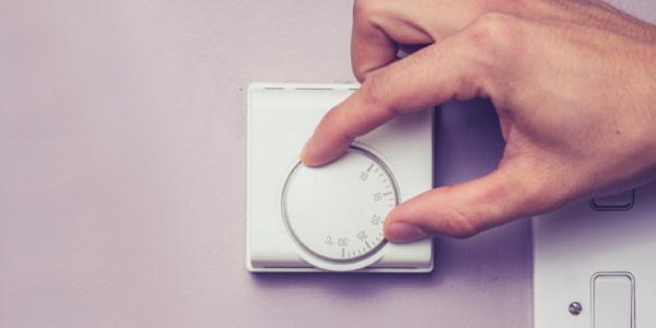 Young woman set the temperature of the water in the electric boiler.