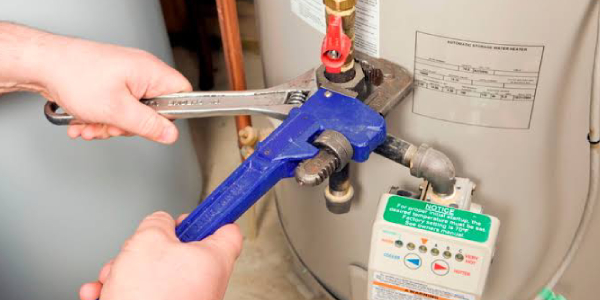 Technician Repairs a water heater with wrench and spanner.